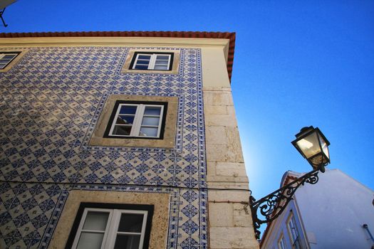 Old colorful and beautiful facades with vintage streetlight in Lisbon streets in Spring. Clothesline in the facade with hanging clothes
