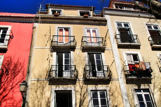 Old colorful and beautiful facades with vintage streetlight in Lisbon streets in Spring. Clothesline in the facade with hanging clothes