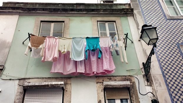 Old colorful and tiled facades with vintage streetlight in Lisbon streets in Spring. Clothesline in the facade with hanging clothes