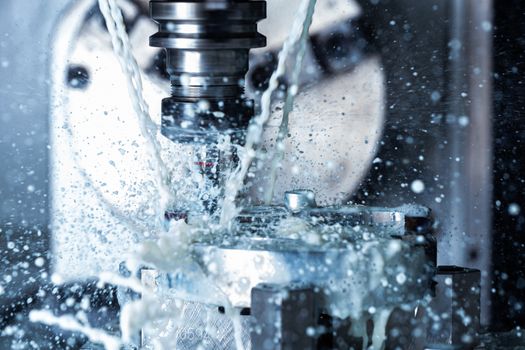 A process of vertical cnc steel milling with external water coolant streams and splashes. Fast shutter speed for motion freezing.