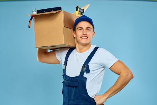 working man in uniform box with tools loader delivery blue background. High quality photo