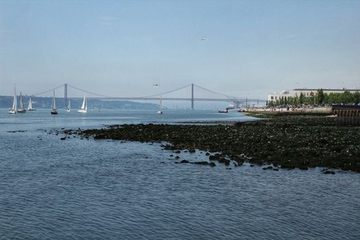 Boats Sailing along the Tagus river in the morning in a sunny day and low tide of Spring in Lisbon
