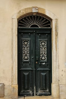 Old wooden door with tiled facade in Lisbon. Wrought metal details on the door.