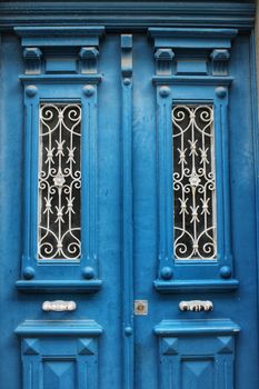 Old wooden door with tiled facade in Lisbon. Wrought metal details on the door.