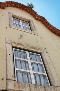 Old colorful and tiled facades with vintage streetlight in Lisbon streets in Spring. Clothesline in the facade with hanging clothes