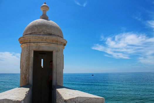 Watchtower of the fortress on the beach in Sesimbra village, Portugal, under blue sky in Spring
