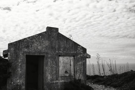 Old abandoned house in Cape Espiche, Portugal. Blue and cloudy sky. Monochrome photography.