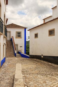 Narrow and colorful streets, majestic facades, windows and balconies of the old village of Obidos, Portugal