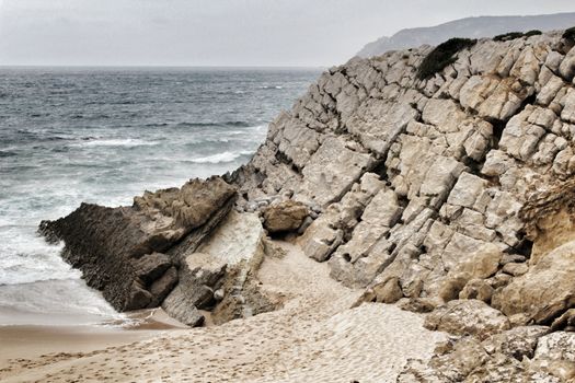 Cliffs and rock formation at Guincho beach under cloudy sky in spring Portugal