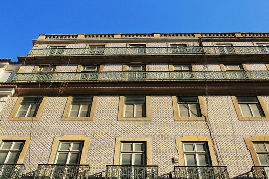 Old colorful and majestic tiled facades with vintage streetlight in Lisbon streets in Spring.