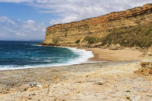 Crystal clear and wild waters in Praia da Foz, Sesimbra, Portugal. Golden sand , seagulls flying, Cliffs and rock formation