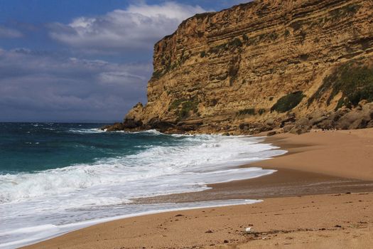 Crystal clear and wild waters in Praia da Foz, Sesimbra, Portugal. Golden sand , seagulls flying, Cliffs and rock formation