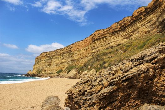Crystal clear and wild waters in Praia da Foz, Sesimbra, Portugal. Golden sand , seagulls flying, Cliffs and rock formation