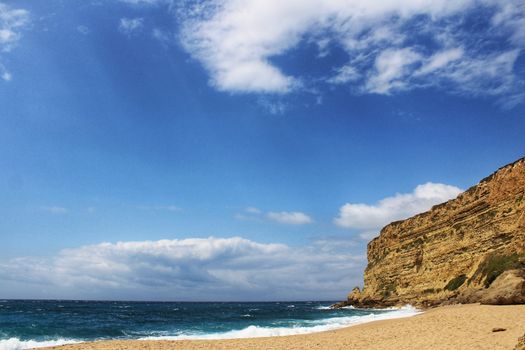 Crystal clear and wild waters in Praia da Foz, Sesimbra, Portugal. Golden sand , seagulls flying, Cliffs and rock formation