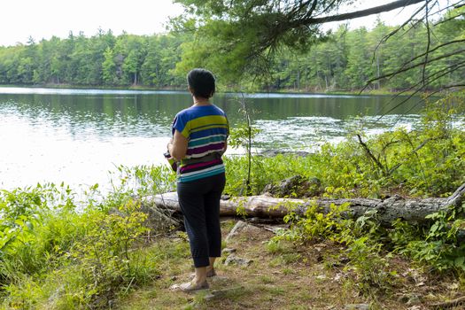 Woman looking at panorama forest lake standing on the shore

