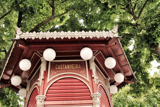 Typical red cafe kiosk in a park in Lisbon, Portugal. Purple tree in the background.