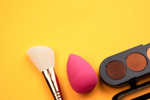 Pink makeup sponge and powder brush yellow background he cropped view. High quality photo