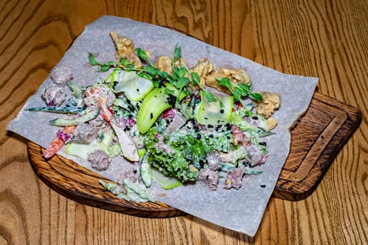 Salad of meat, vegetables and greens. Salad on a wooden board