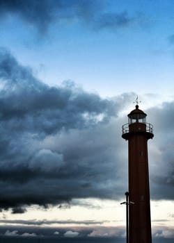 Red lighthouse in the port of Cacilhas village in Lisbon on a gray and cloudy day