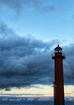 Red lighthouse in the port of Cacilhas village in Lisbon on a gray and cloudy day