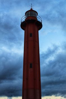 Red lighthouse in the port of Cacilhas village in Lisbon on a gray and cloudy day