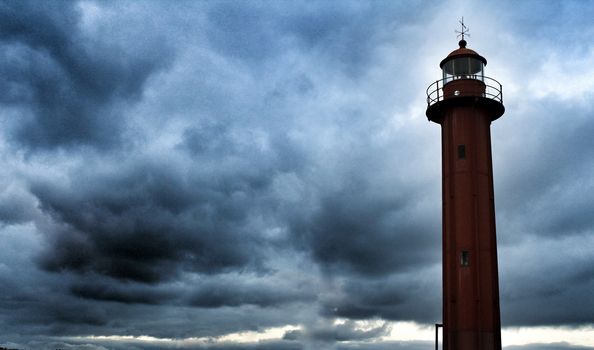 Red lighthouse in the port of Cacilhas village in Lisbon on a gray and cloudy day