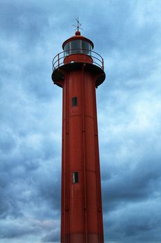 Red lighthouse in the port of Cacilhas village in Lisbon on a gray and cloudy day