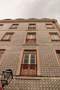 Old colorful and majestic tiled facades with vintage streetlight in Lisbon streets in Spring.