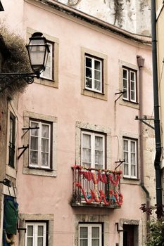Old colorful and tiled facades with vintage streetlight in Lisbon streets in Spring. Clothesline in the facade with hanging clothes
