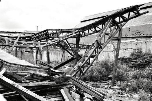 Old abandoned factory with destroyed wooden beams. Monochrome photography.