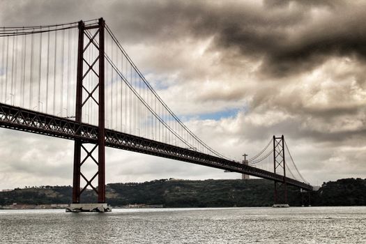 Banks of the river Tagus in Lisbon in Spring on a cloudy day. Beautiful 25th April bridge structure.