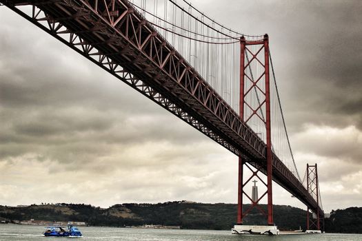 Lisbon, Portugal- June 1, 2018:Banks of the river Tagus in Lisbon in Spring on a cloudy day. Beautiful 25th April bridge structure.