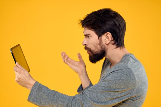 Bearded man with tablet in hands technology work wireless device yellow background. High quality photo