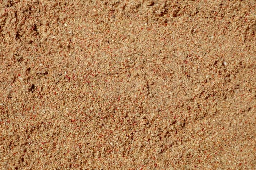 Dead red coral mixed with white sand become pink. Background macro texture. Pieces of red corals that has been taken by waves into the shore. Close up of sand with fragments of red coral.