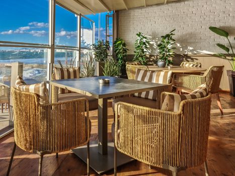 Day sunny view of no people space with chairs & ashtrays on tables with a glass panel before the seafront in Thessaloniki, Greece.