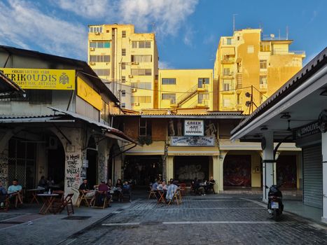 Crowd eating & drinking at a pedestrian area taverna in the center at Kapani market area.