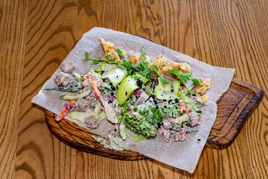 Salad of meat, vegetables and greens. Salad on a wooden board