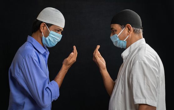 Two muslim men in medical mask greeting or salam each other in Islamic way while Maintaining social distancing - Concept of Coronavirus or covid-19 safety measures and new normal lifestyle