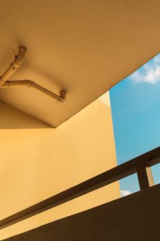 sewer pipes or drain pipes on yellow building wall with beautiful blue sky