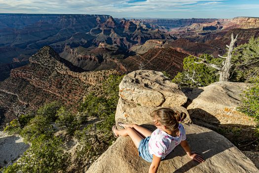 Teenage girl sitting on the edge of the rim of Grand Canyon National Park, Arizona, USA