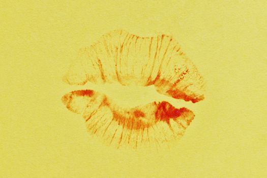 Red lipstick kiss on yellow paper background