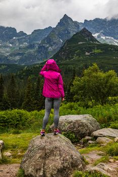 Hooded woman looking at the Tatra mountain panorama in the rain - portrait orientation