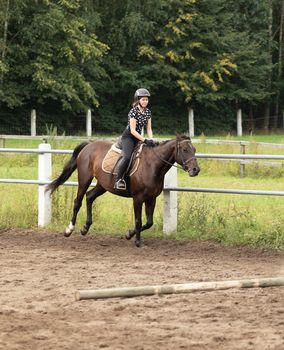 Teenage girl in gallop horseback riding in stables