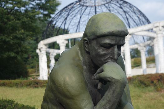 CHUNCHEON, SOUTH KOREA- JANUARY-10, 2019: Green statue of thinker Auguste Rodin, setting naked on a rock in a public park