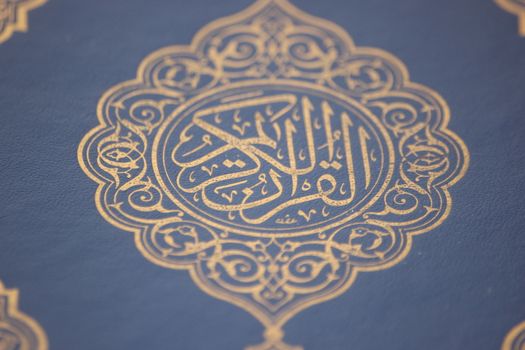 Closeup shot of Islamic Book Quran with golden arabic calligraphy that means Al-Quran, the Holy Quran