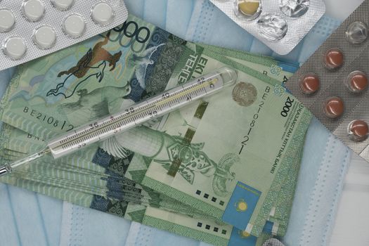 Thermometer, tablet, medical mask and tenge money are on the table. Increase in the price of medicines in Kazakhstan in tenge KZT. Kazakhstan is quarantined due to the coronavirus and flu epidemic.