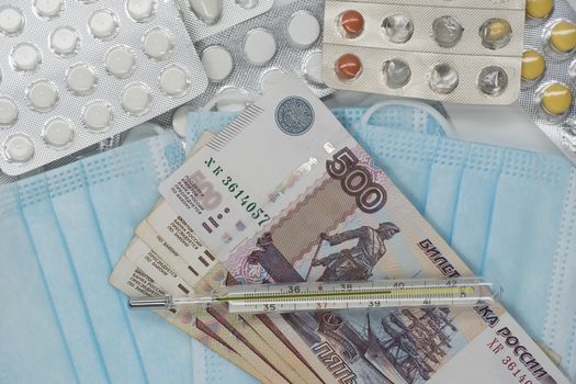 A thermometer, a pill, a medical mask and money in Rubles are on the table. Increase in prices for medicines in Russia in Rubles. Russia is on quarantine because of the epidemic of the coronavirus