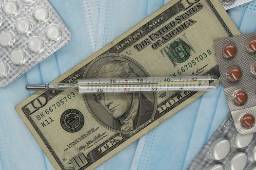 On the table is a thermometer, a pill, a medical mask, and money in dollars. The growth of prices for medicines in America in dollars.The United States is under quarantine of the epidemic coronavirus