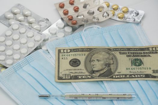 On the table is a thermometer, a pill, a medical mask, and money in dollars. The growth of prices for medicines in America in dollars.The United States is under quarantine of the epidemic coronavirus