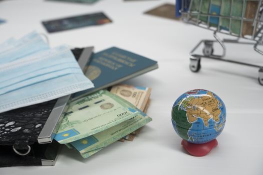 Quarantine in Kazakhstan. Tenge money with medical face masks, a globe, a card and a passport are on the table. The closure of borders and travel in Kazakhstan.